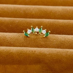 Macro view of gold cartilage stud with green marquise gems and white round zircons