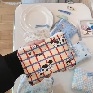 Close-up of mini canvas dog pattern pouch with blue zipper pull and simple tag