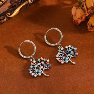 Detail of silver tree of life earrings with multicolored crystals on vintage background