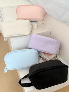 Stack of macaron-colored travel toiletry bags in pink beige lavender and blue