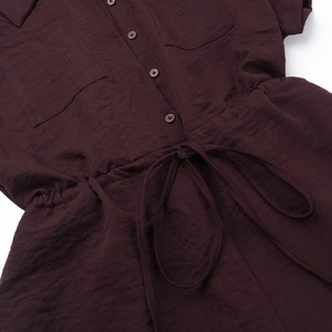 Detailed macro view of dark purple textured fabric with buttons and waist drawstring detail