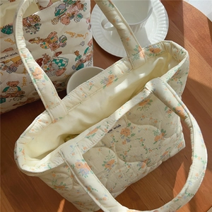 Vue macro de sacs en coton matelassé avec motifs floraux et ours sur table en bois