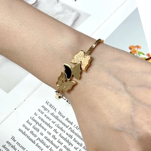 Detail of gold butterfly bangle featuring black, champagne, and glitter resin charms