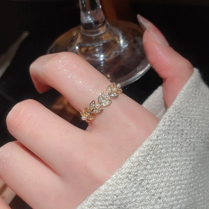 Macro shot of gold wheat leaf ring with pearls and zircons worn on model's finger