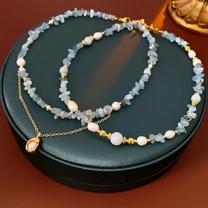 Detail of layered necklace with freshwater pearls, blue stones, and shell pendant