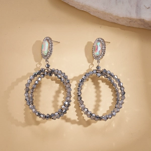 Detail of hollow geometric earrings featuring grey faceted beads and crystal studs