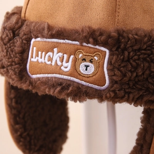 Detail of winter trapper hat featuring plush faux shearling lining and Lucky bear patch