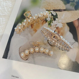 Detail of three gold alloy claw clips set with elegant white pearls on a magazine backdrop