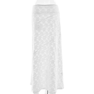Close-up of the delicate lace floral patterns and textured white fabric of the maxi skirt