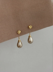 Close-up of elegant gold textured stud with a champagne teardrop pearl hanging from fabric