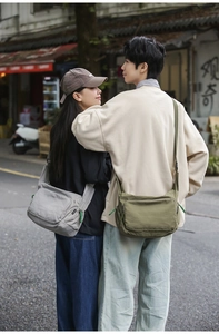 Waterproof nylon messenger bags in grey and army green worn by a couple on the street