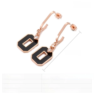 Macro detail of geometric rose gold earrings with black resin inlay and zircon stone