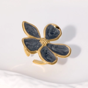 Détail macro d'une bague fleur dorée avec pétales en émail gris foncé et pistil en métal