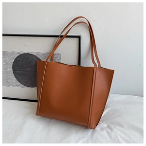 Detailed view of brown faux leather tote bag with slim shoulder straps and minimalist design