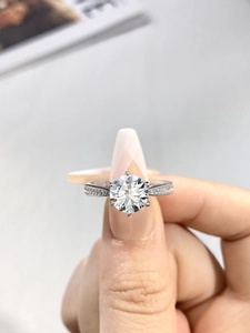 Macro shot of a classic six-prong moissanite ring with side stones on a 925 silver band
