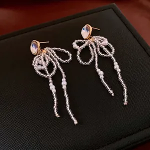 18k gold-plated bow pearl tassel earrings with crystal studs on a black jewelry box