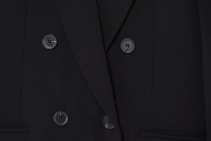 Détail d'un blazer noir classique à double boutonnage avec boutons en résine et sergé