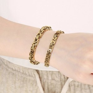 Close-up of gold Byzantine weave bracelets in thick and thin styles on a model wrist