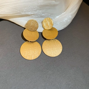 Detailed view of golden triple circle earrings with brushed metal texture and retro design