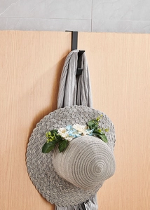 Close-up of black metal portable desk hook hanging a floral straw hat and a grey scarf