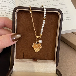 Detailed shot of 18K gold plated maple leaf necklace with pearls on a velvet box