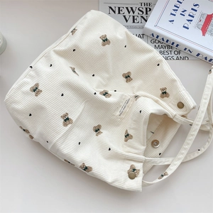 Detail of corduroy tote bag with bear print featuring magnetic buckle and soft texture