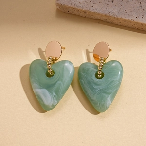Close-up of green marble textured resin heart earrings with gold beaded metal accents