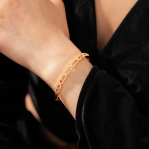 Detailed view of a gold bangle featuring oval Triomphe links with white zircon inlay