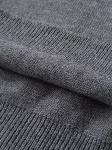 Macro shot of dark grey knit sweater showing smooth jersey stitch and elastic ribbed hem
