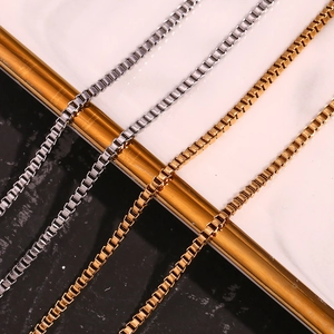 Close-up of gold and silver stainless steel box chains on black marble background