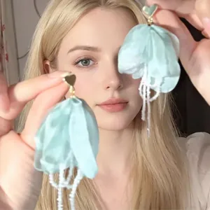 Detail of mint green floral fringe earrings with white beads and gold heart studs