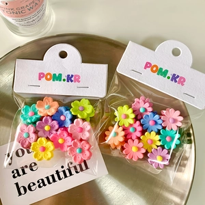 Macro shot of colorful candy-colored flower hair clips in a modern metallic tray