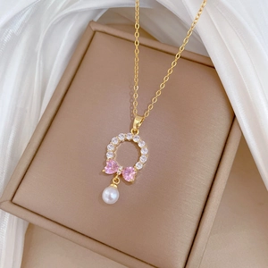 Detailed macro view of bow necklace with pink crystal, diamonds and pearl in a jewelry box