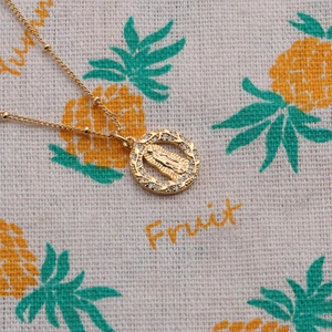 Detail shot of a gold-plated Virgin Mary pendant with sparkling zircon insets