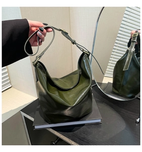 Detail of dark green glossy hobo bag with adjustable strap and gold buckle reflection