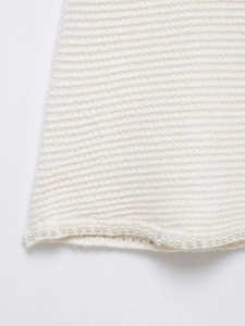 Gros plan sur un tissu en maille blanche avec texture côtelée et détails en perles