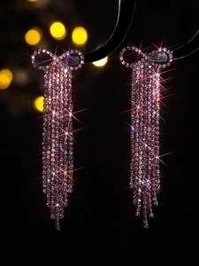 Close-up of pink rhinestone tassel earrings with a crystal bow and sparkling light effect