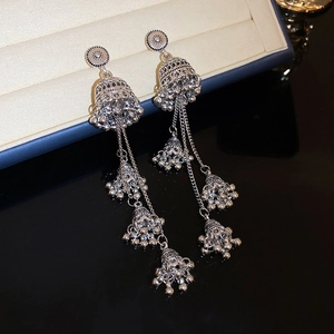 Detail of silver vintage Jhumka earrings with layered tassels and engraved metal texture