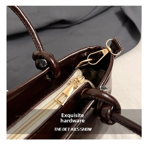 Détails de la fermeture éclair dorée et des finitions métalliques sur un sac seau marron