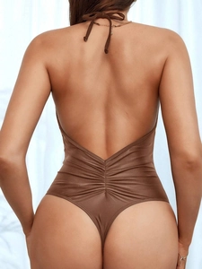 Detail of ruched back design on brown backless one-piece swimsuit with high cut leg