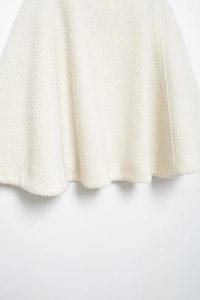 Detailed close-up showing the textured white fabric and elegant hemline of the skirt