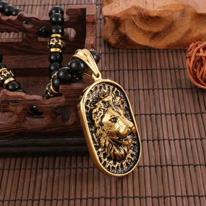 Close-up of a golden lion head pendant with black onyx beads on a wooden background
