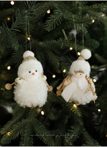 Detail of plush white Christmas ski character ornaments hanging on a festive tree branch