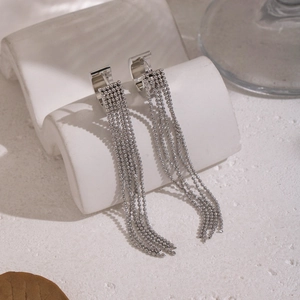 Detail of silver long tassel drop earrings with beaded chains on a modern display