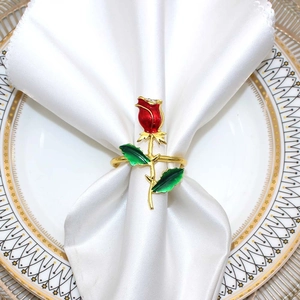 Detail of a red rose napkin ring with green leaves on a white linen napkin