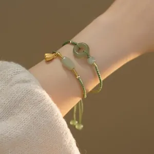 Detail of hand-woven green bracelets with lotus charm and jade donut on model's wrist