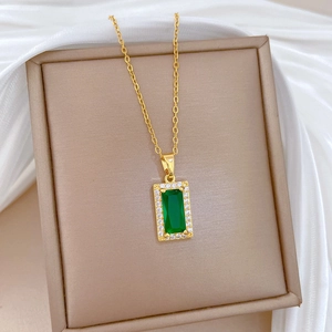 Luxurious gold necklace with emerald rectangle pendant and diamonds in a jewelry box