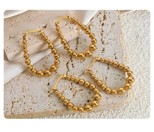 Dettaglio orecchini a cerchio con perle in oro 18K su marmo e seta bianca