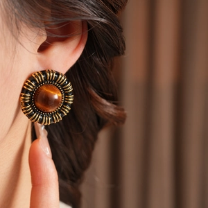 Close-up of vintage resin heart earring with golden spiral texture on model's ear