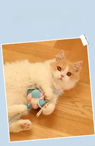 Cat teaser wand with macaron plush balls and ribbons shown with an orange tabby cat
